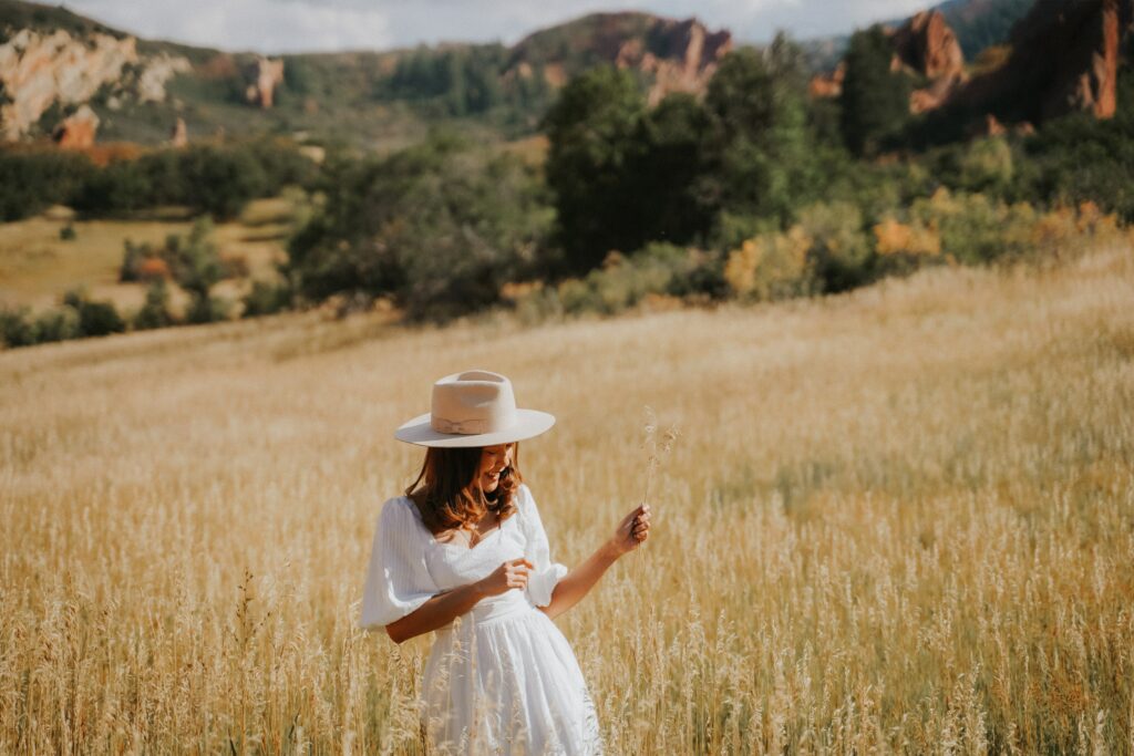 Frau mit weißem Kleid und Hut bei Sommerhochzeit