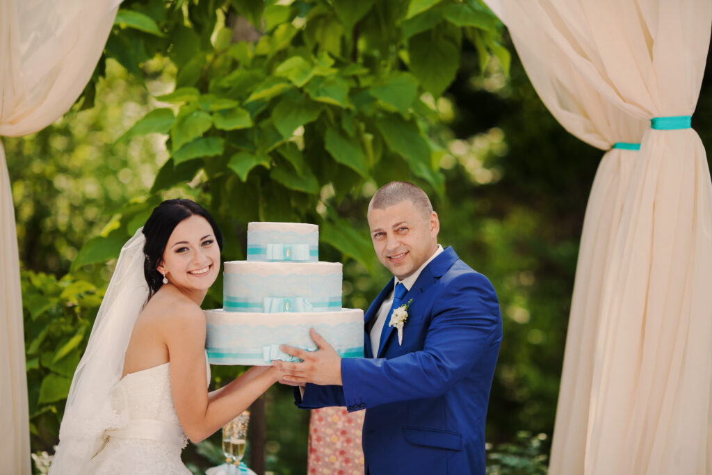 Das Brautpaar hält ihre Hochzeitstorte in der Hand